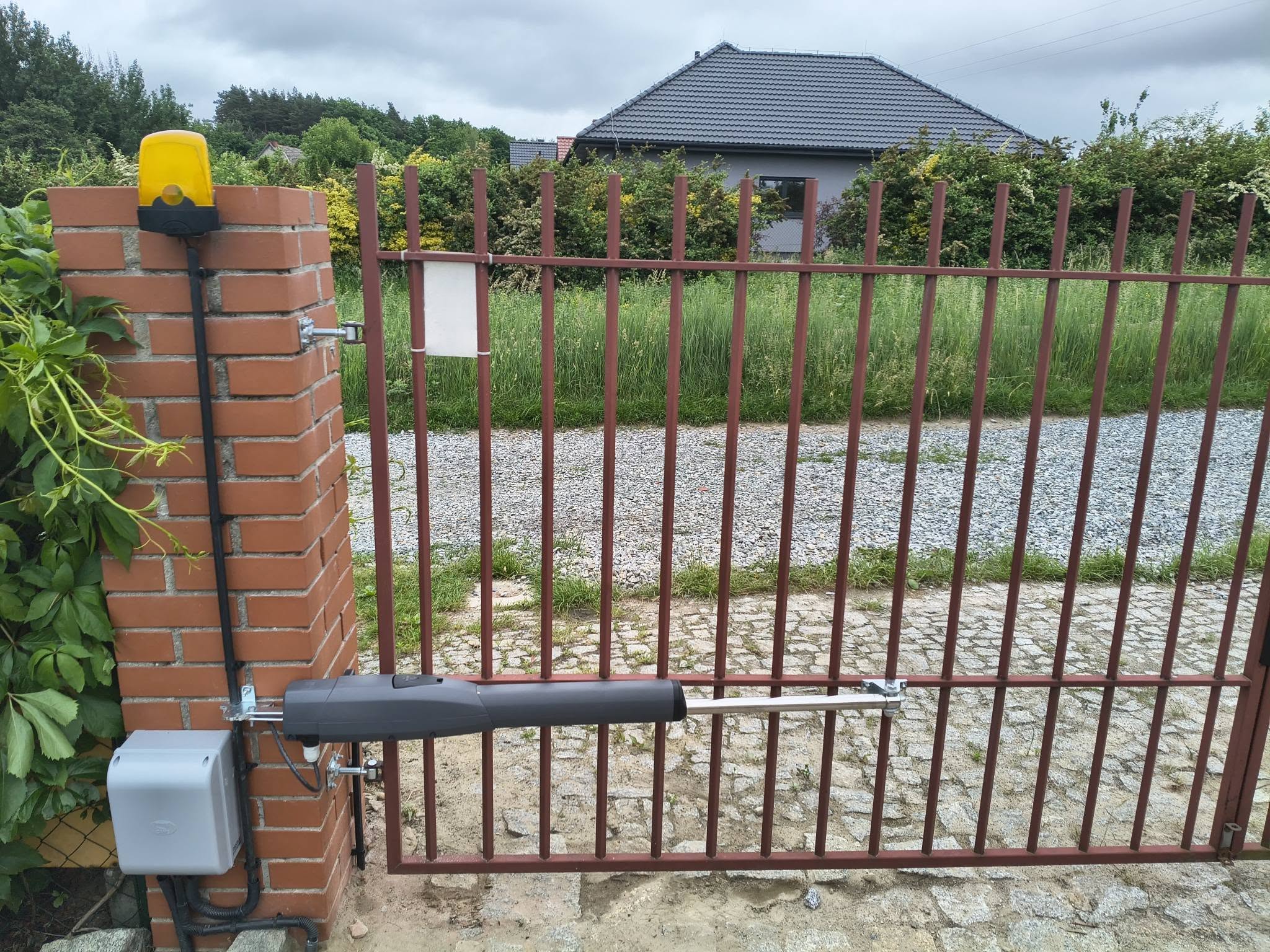Brama skrzydłowa z napędem, lampą ostrzegawczą i sterownikiem na murowanym słupku